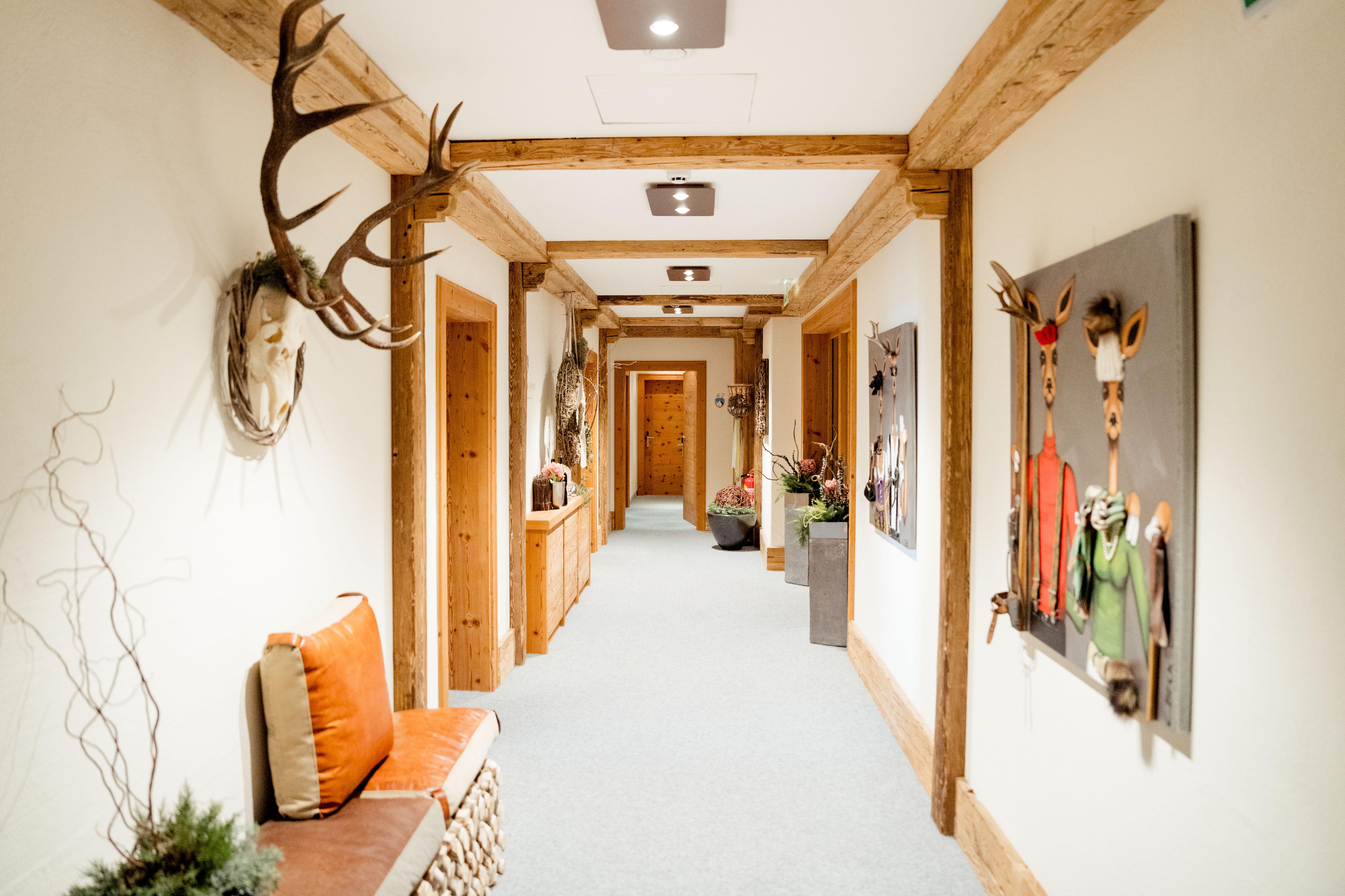 Heller Flur mit Holzrahmen, Wanddekorationen und einem Sitzbereich mit Kissen, dekoriert im rustikalen Stil.