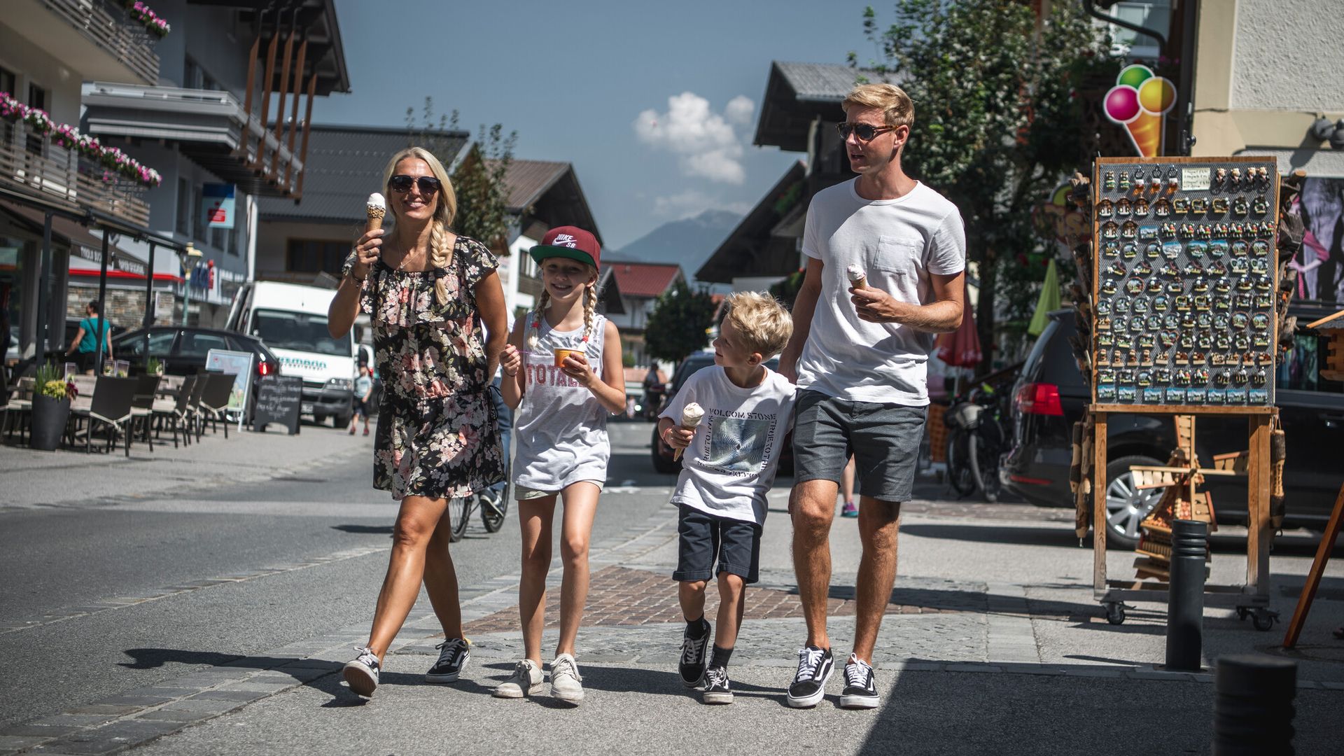 Hauptstraße Mayrhofen Family - mom, dad and 2 children, a boy and a girl, walk along Mayrhofen's main street with an ice cream.