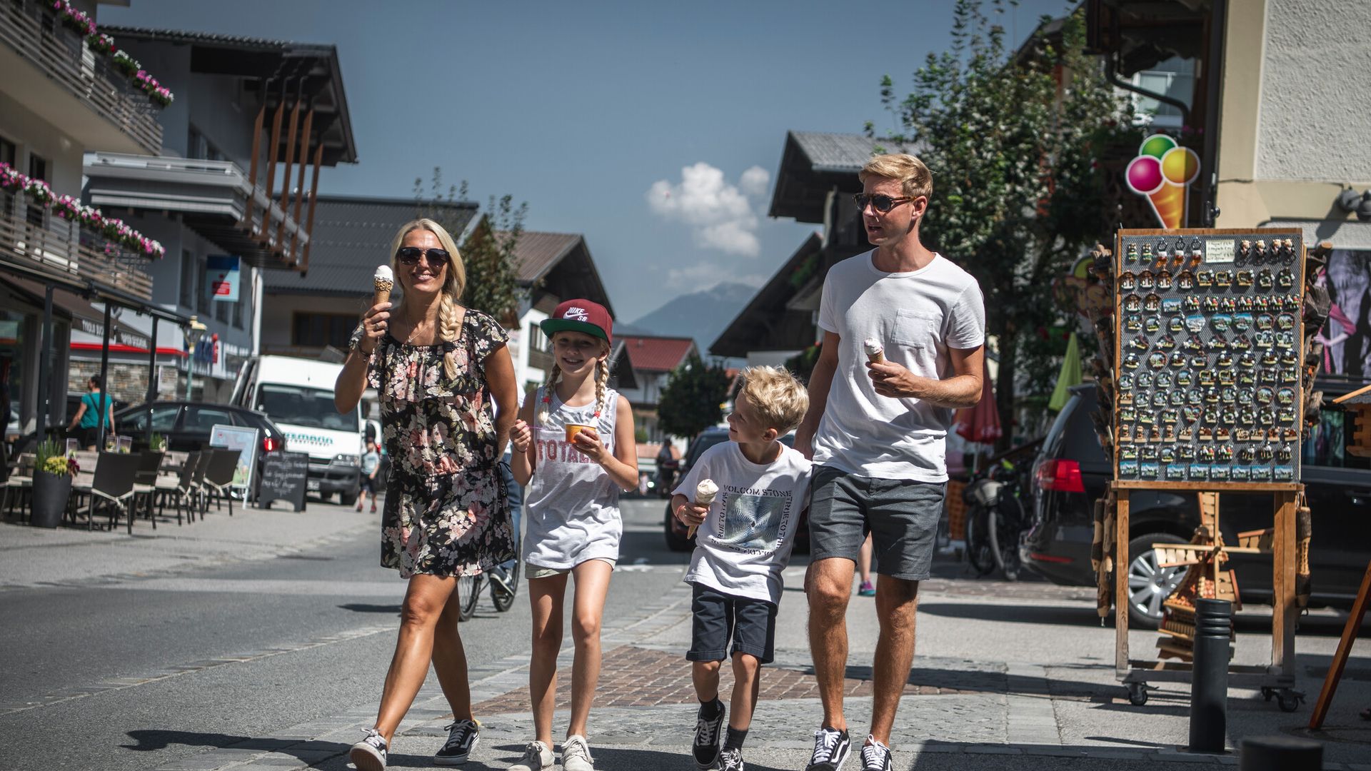 Hauptstraße Mayrhofen Family - mom, dad and 2 children, a boy and a girl, walk along Mayrhofen's main street with an ice cream.