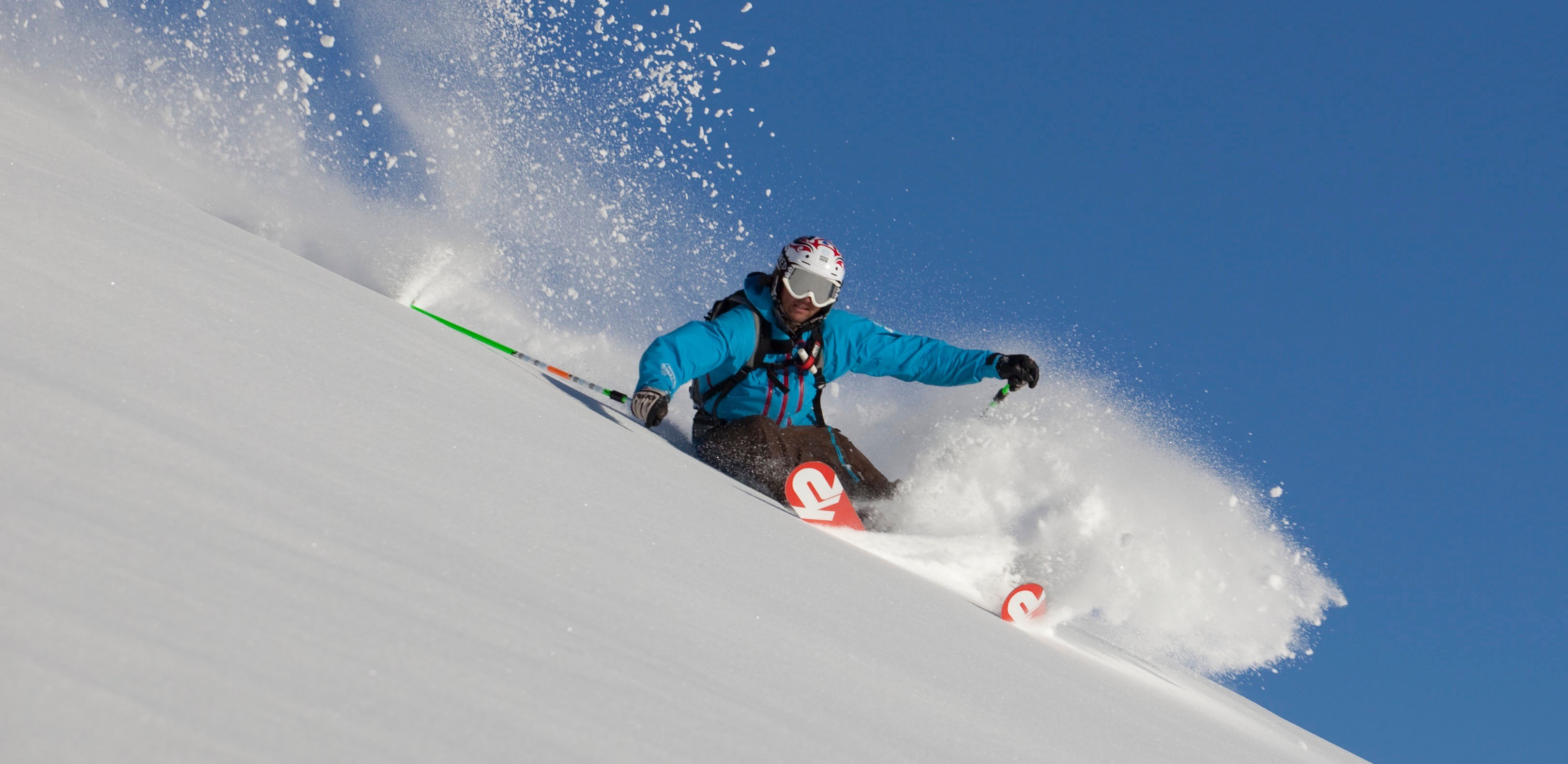 Freeride skiing in the Zillertal near Mayrhofen, Austria – skier carving through fresh powder snow on a sunny day.
