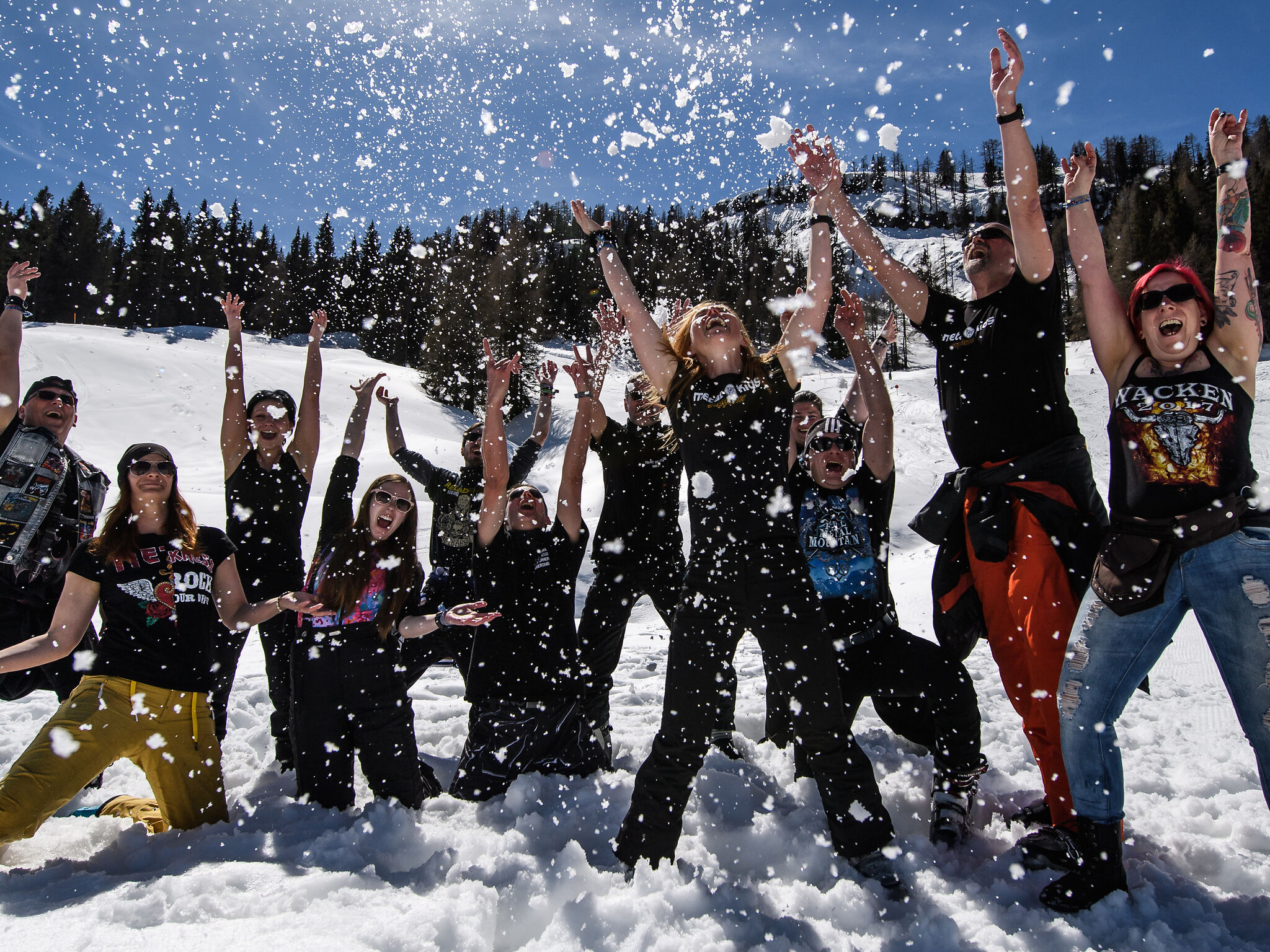 Das Bild zeigt eine Gruppe von Menschen im Schnee, die Schnee in die Luft werfen
