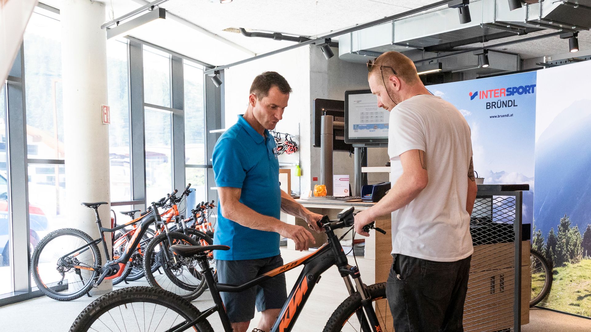 Two men at a modern bike service station in Mayrhofen-Hippach, Zillertal. On-site support for repairs, maintenance, and e-bike services for cyclists.