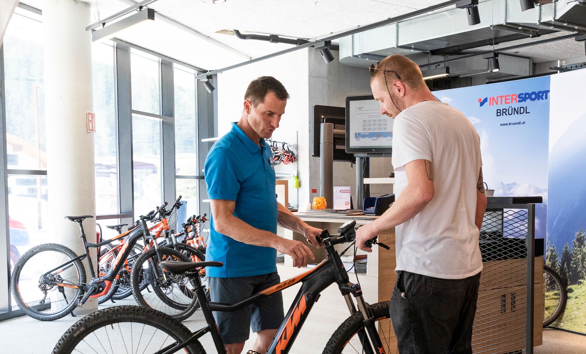 Two men at a modern bike service station in Mayrhofen-Hippach, Zillertal. On-site support for repairs, maintenance, and e-bike services for cyclists.