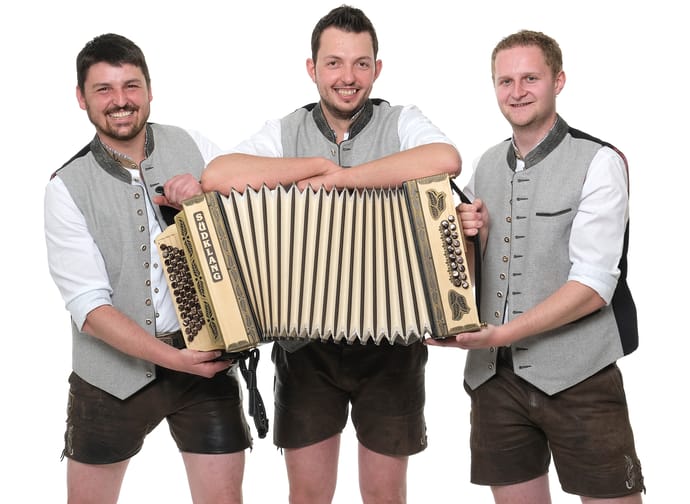Das Bild zeigt die Musikgruppe Schneidig & Echt auf einem Gruppenbild mit Ziehharmonika im Vordergrund.