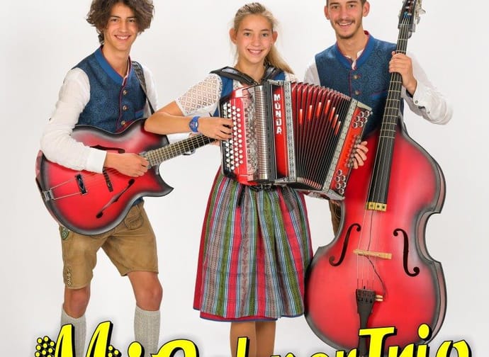 Das Bild zeigt das Mißebner Trio mit ihren Instrumenten sowie den Namen der Gruppe in gelber Schrift.