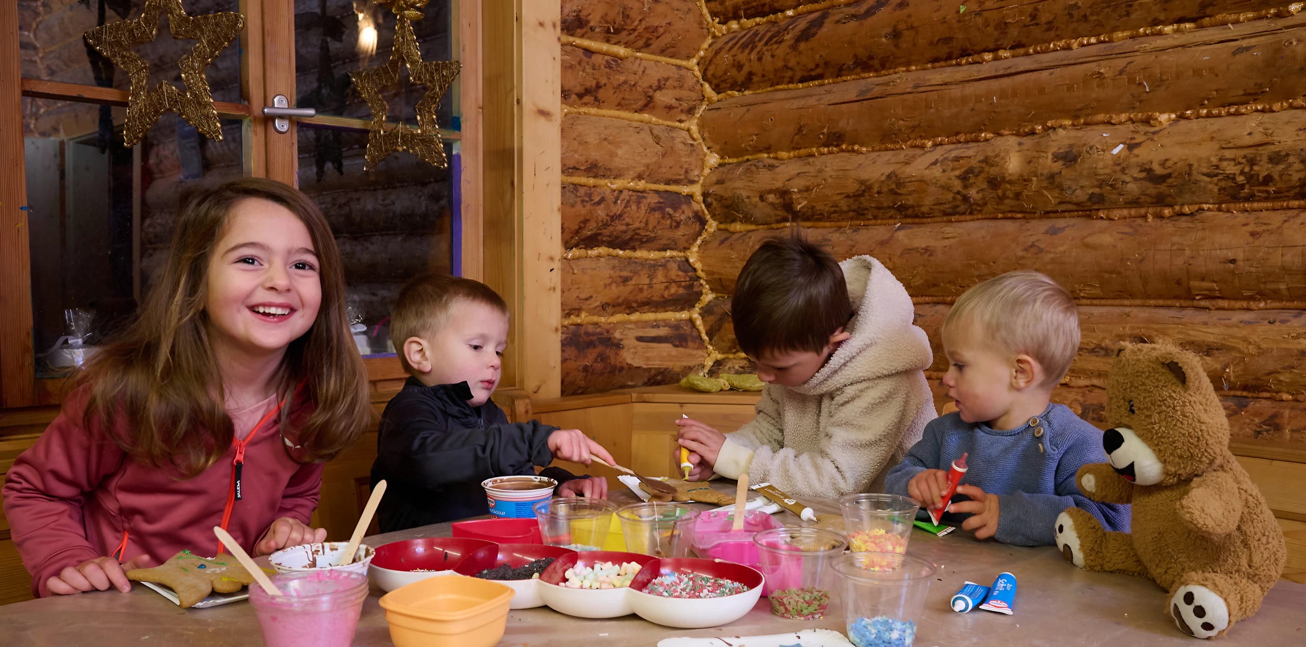 4 Kinder sitzen an einem Tisch und verzieren Lebkuchen 