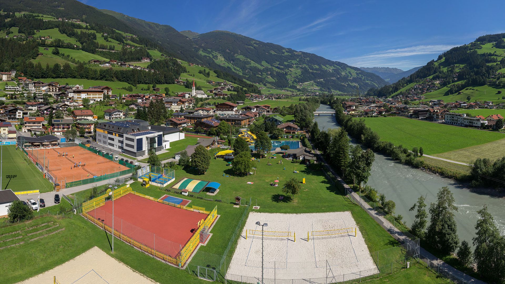 Four well-maintained clay tennis courts at Sommerwelt Hippach in the Zillertal valley, surrounded by alpine scenery – perfect for playing tennis in Tyrol with a mountain view.
