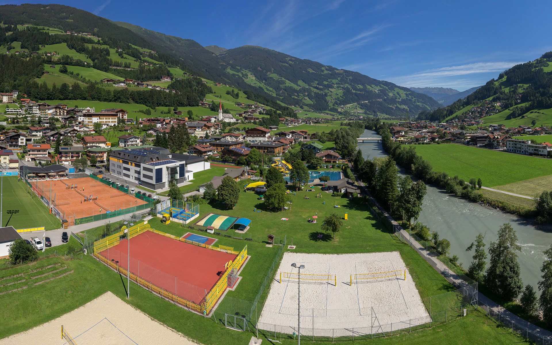 Four well-maintained clay tennis courts at Sommerwelt Hippach in the Zillertal valley, surrounded by alpine scenery – perfect for playing tennis in Tyrol with a mountain view.