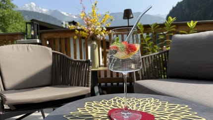 Zwei schwarze Stühle mit einem Weinglas gefüllt mit einem Sekt, Erdbeeren und einer Zitronescheibe