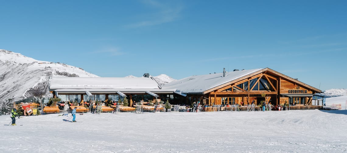 A ski lodge surrounded by snow and blue skies.