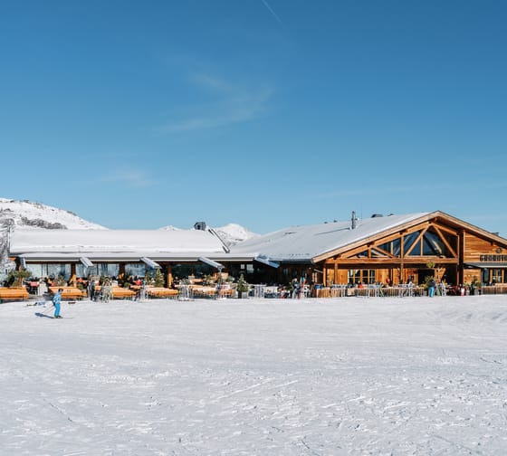 Eine Skihütte umgeben von Schnee und blauer Himmel.