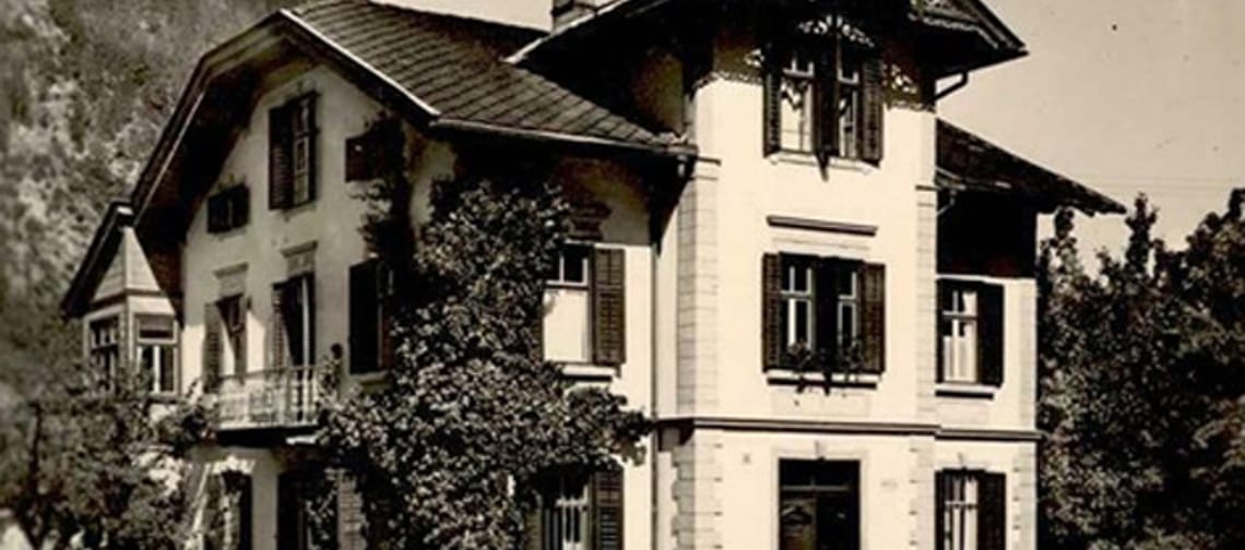 Historical postcard: Fischnaller House in Mayrhofen, Tyrol – traditional Alpine-style house with bay window and balcony, garden fence and mountain backdrop.