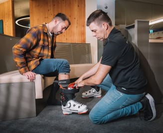 Skischuhverleih im Zillertal, Tirol: Mitarbeiter passt einem Gast den Skischuh an – professioneller Service für Skifahren im Winterurlaub in Mayrhofen-Hippach.