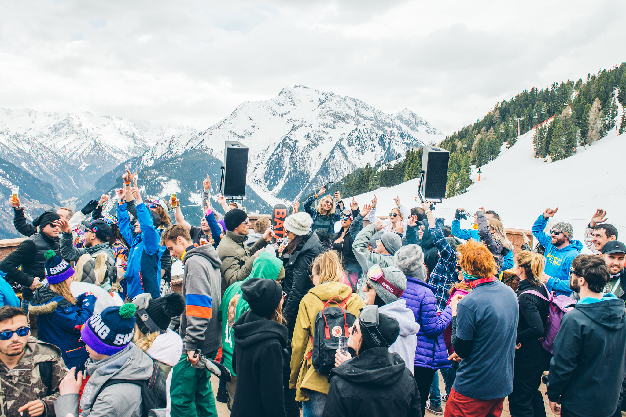 Das Bild zeigt eine Party im Freien auf dem Berg mit feiernden Menschen im Vordergrund und einem DJ im Hintergrund.