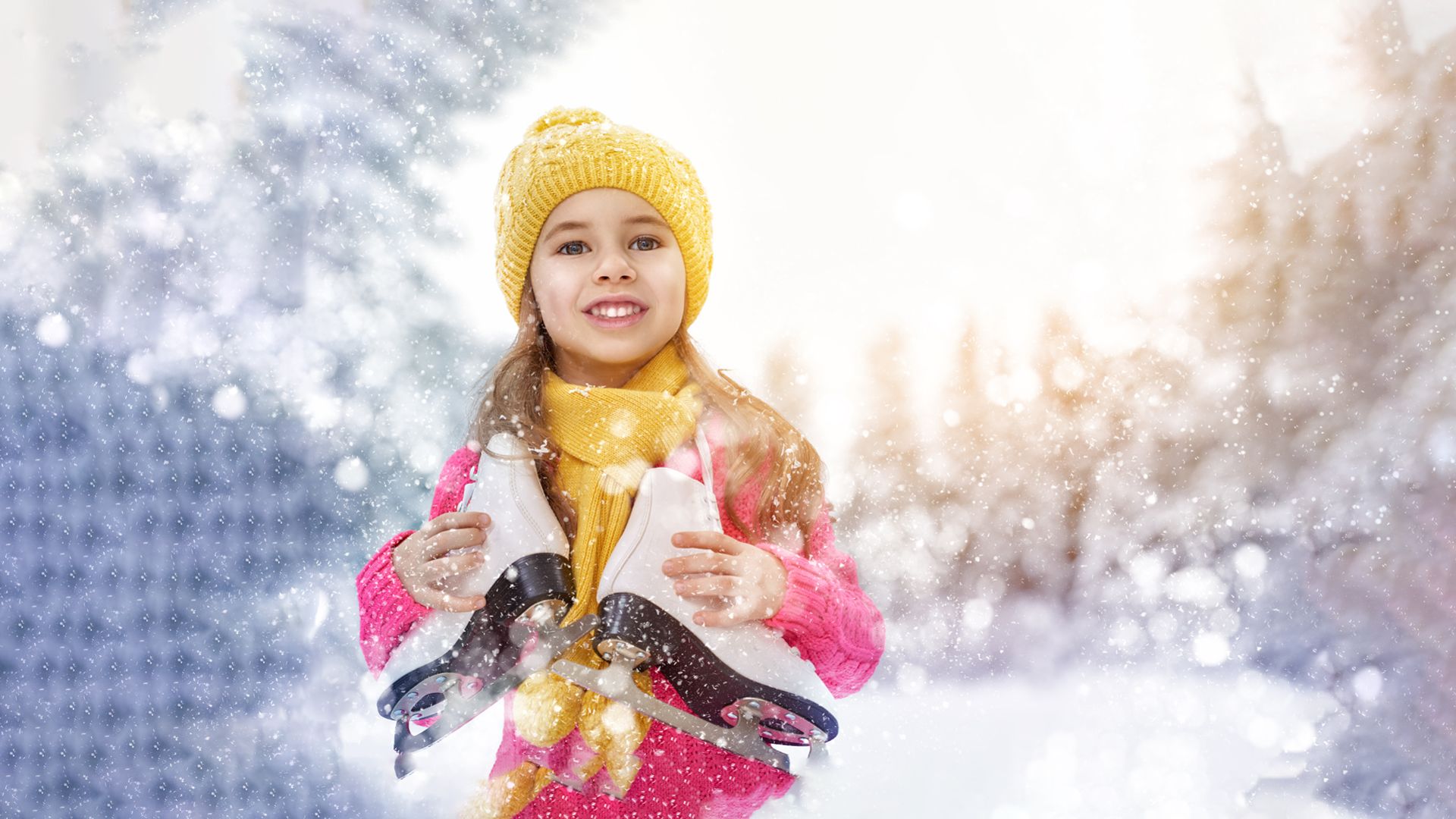 Mädchen mit gelber Mütze hält ein Paar Schlittschuhe vor einer verschneiten Winterlandschaft mit Lichtern. Symbolbild für Eislaufen in Mayrhofen im Zillertal und fröhliche Wintertage mit der Familie.