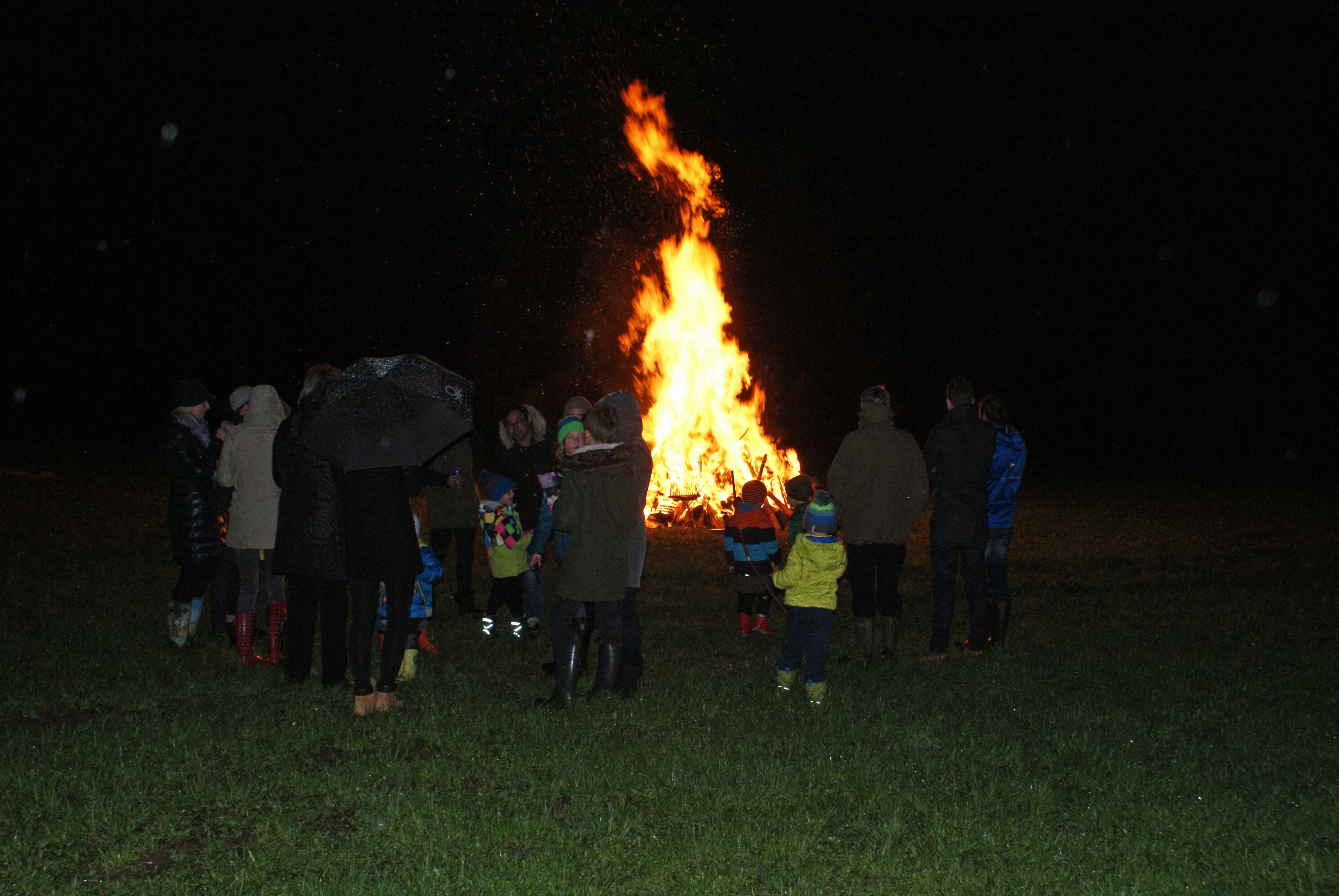 People stand in a circle around a bright, blazing Easter fire in Mayrhofen, Zillertal. Young and old gaze into the flames that light up the dark night. This tradition brings the community together.