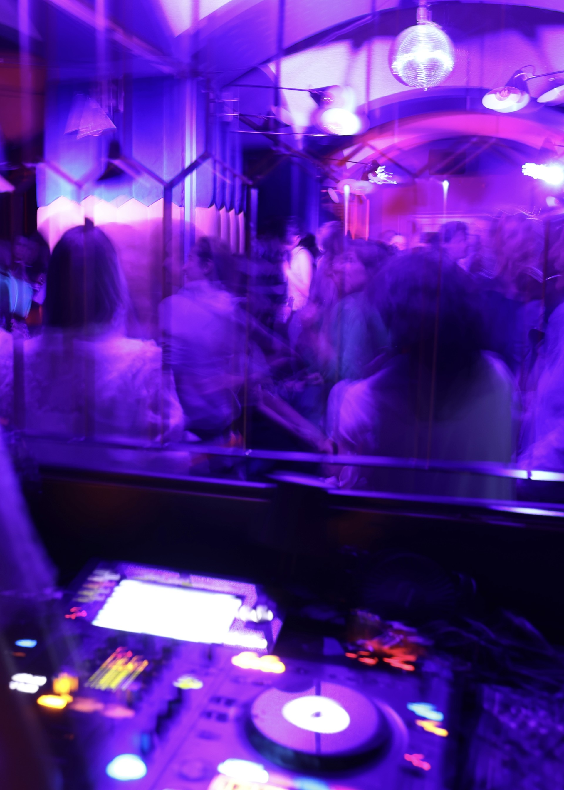 Dunkler Club mit tanzenden Menschen und bunten Lichtern, die eine lebhafte Atmosphäre schaffen.