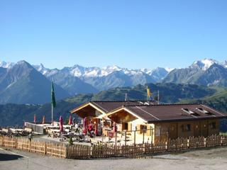 The image shows the Melchboden snack station on the Schwendberg with a terrace and a mountain panorama in the background.