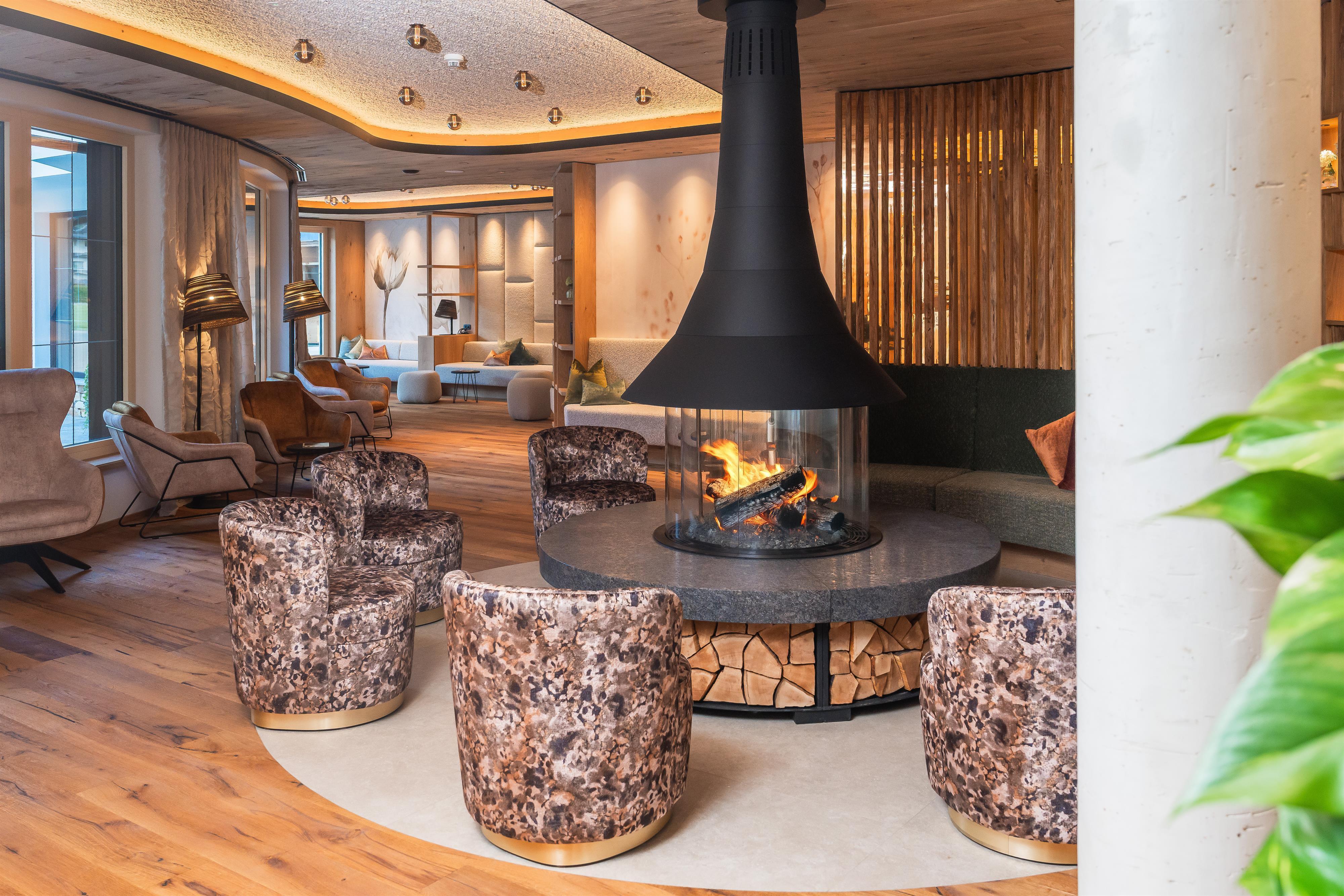 Gemütliche Lounge mit Kamin, bequemen Sesseln, Holzdecke und warmem Licht, gemütlich und einladend.