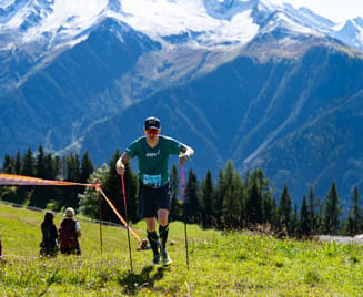 Trailrunner beim Mayrhofen Ultraks Zillertal auf einem Bergweg oberhalb von Mayrhofen; im Hintergrund Almwiesen, bewaldete Hänge und die Gipfel der Zillertaler Alpen.