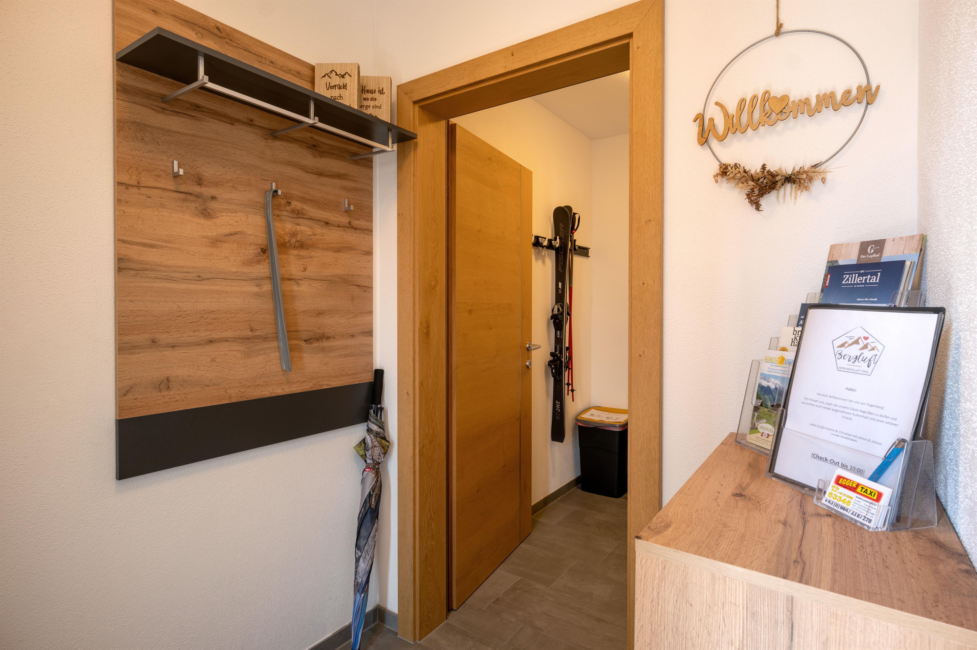 View of a hotel reception area with a welcome sign, brochures, and a coat rack with hooks.