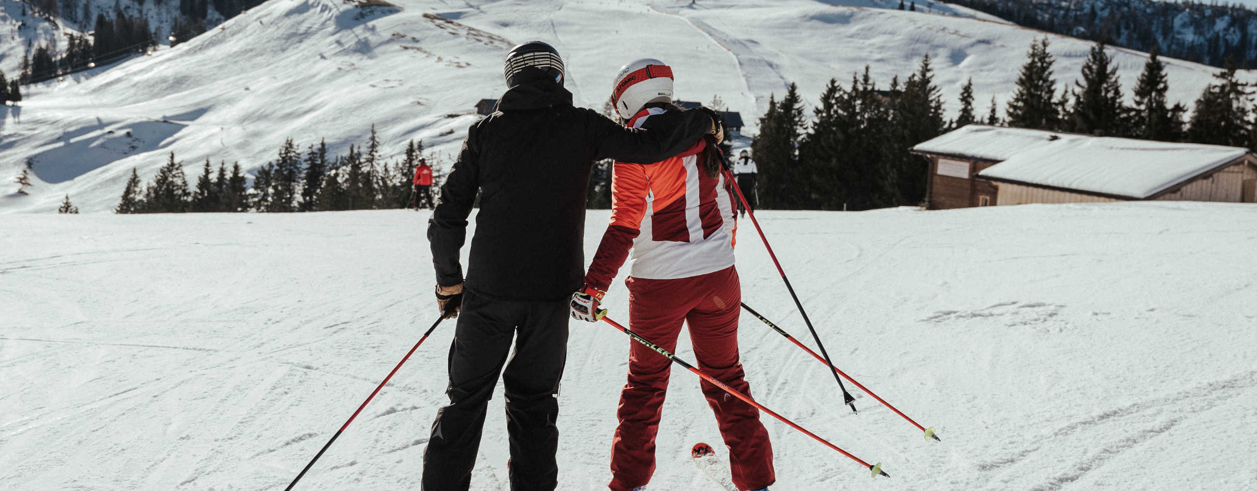 Two skiers in the Almenwelt Lofer, with a view of the snow-covered Loferer Steinberge and the expansive winter landscape of the Salzburg Alps.