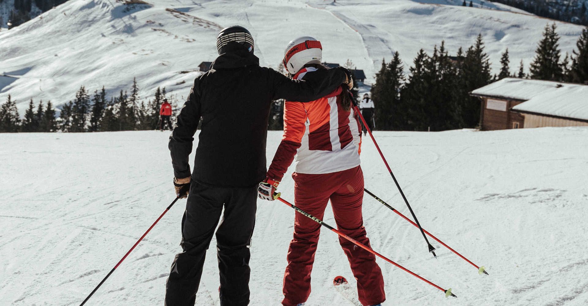 Two skiers in the Almenwelt Lofer, with a view of the snow-covered Loferer Steinberge and the expansive winter landscape of the Salzburg Alps.