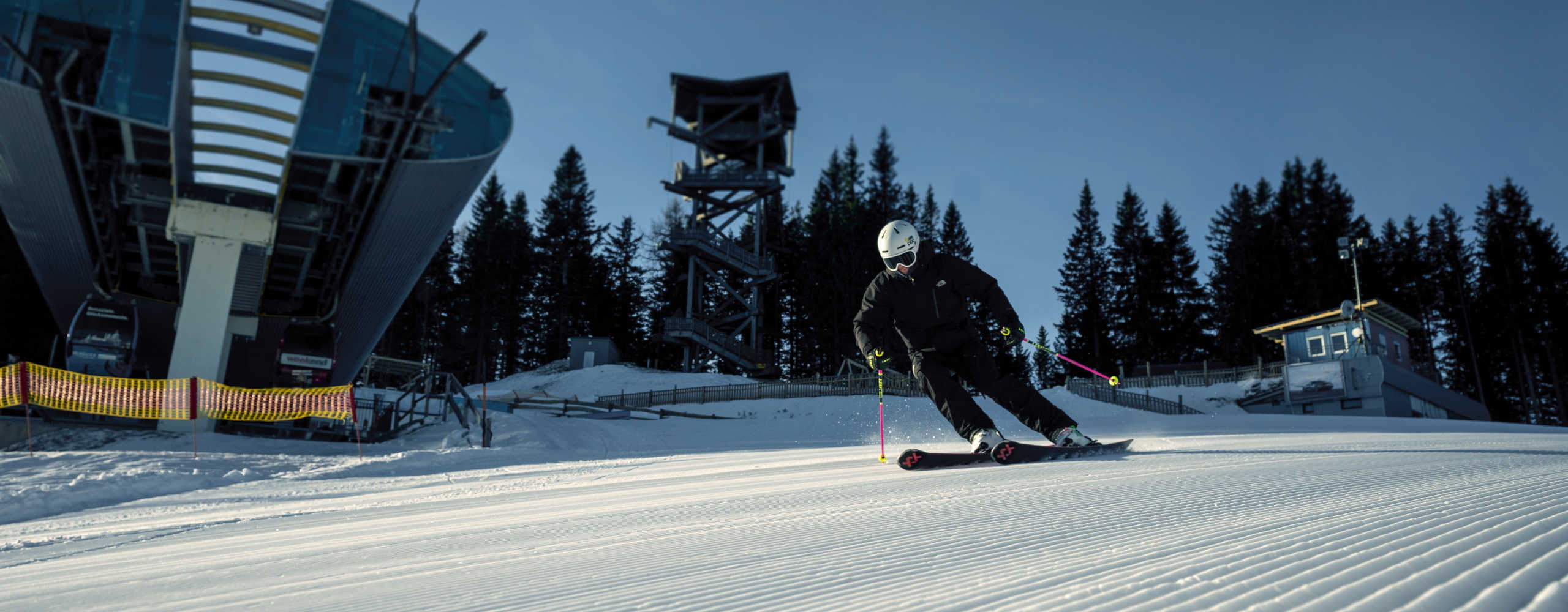 Skifahrer am Semmering-Hirschenkogel bei einer Carving-Abfahrt auf einer frisch präparierten Piste vor der Talstation der Seilbahn.
