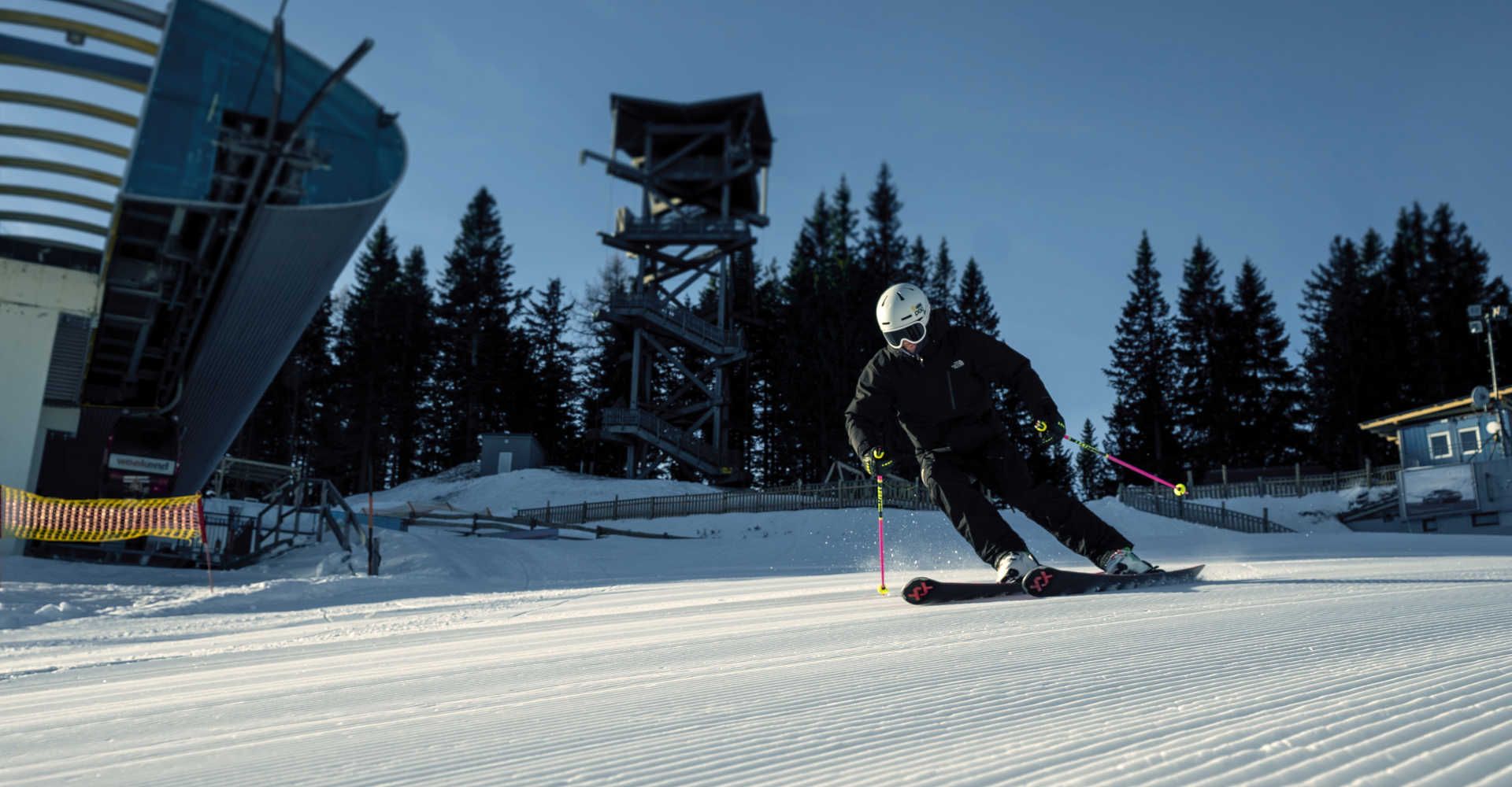 Skifahrer am Semmering-Hirschenkogel bei einer Carving-Abfahrt auf einer frisch präparierten Piste vor der Talstation der Seilbahn.