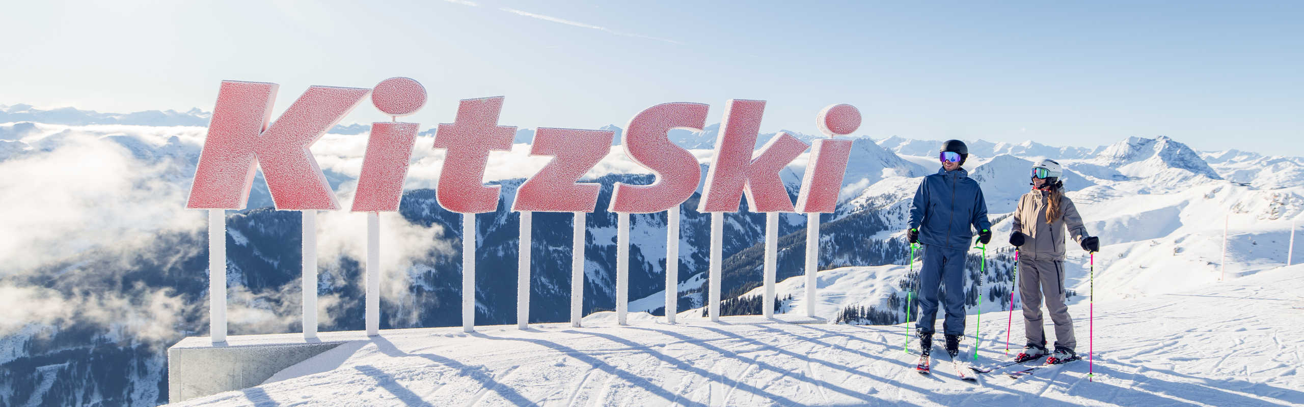 KitzSki panoramic viewpoint in Kitzbühel, featuring skiers and a breathtaking Alpine panorama.