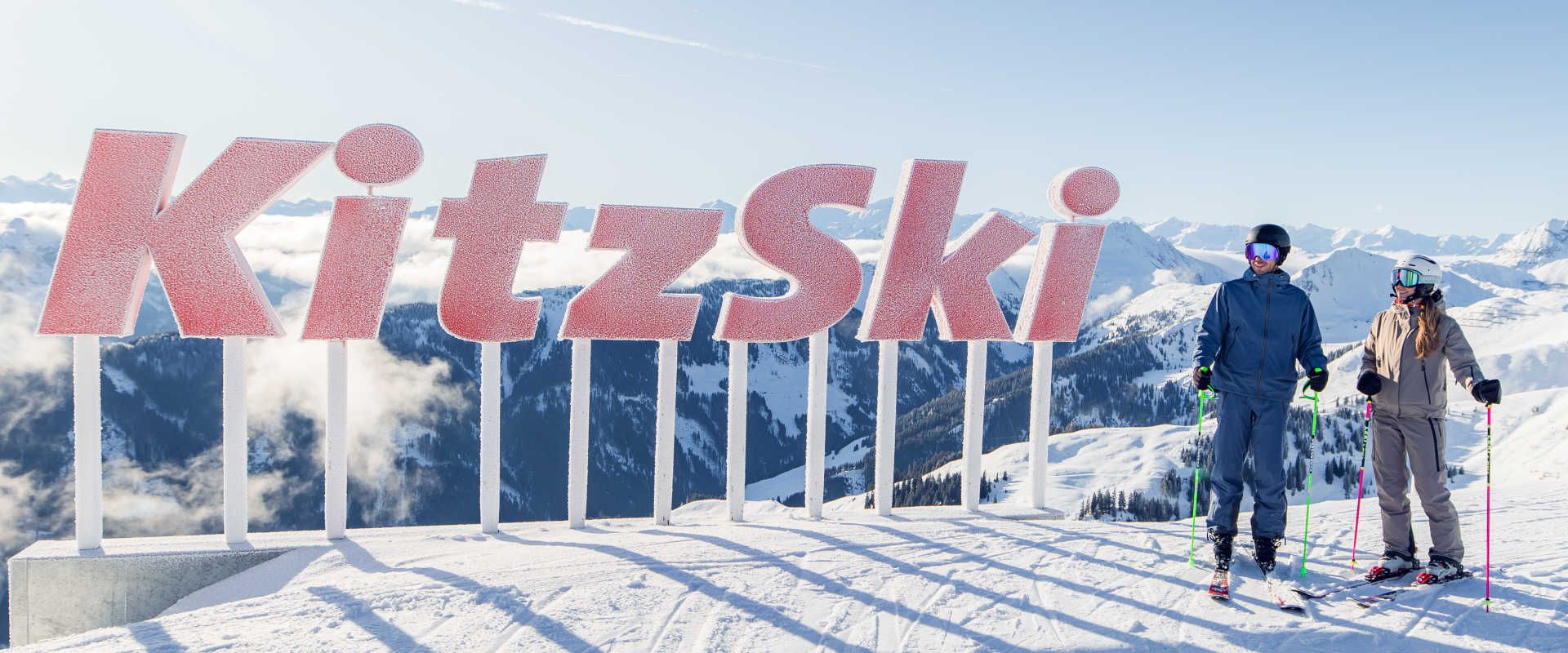 KitzSki panoramic viewpoint in Kitzbühel, featuring skiers and a breathtaking Alpine panorama.