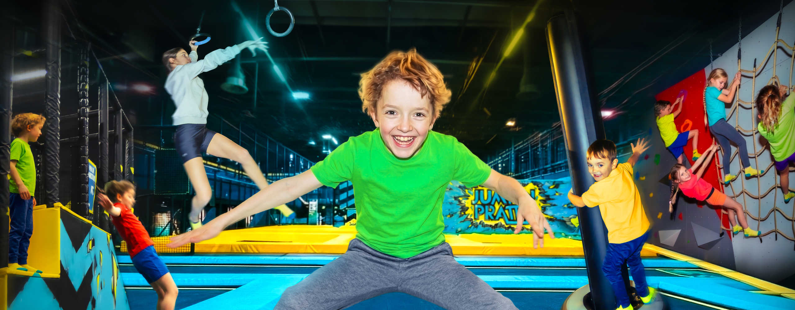Kind mit grünen Top am Trampolin springend 