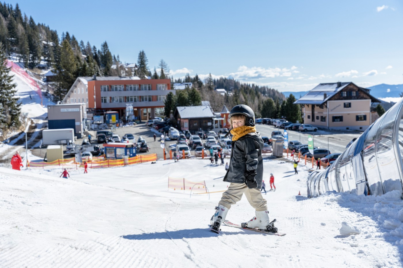 A young skier on a beginner's slope at Klippitztörl in Carinthia, with sunny winter weather and a snow-covered mountain backdrop.