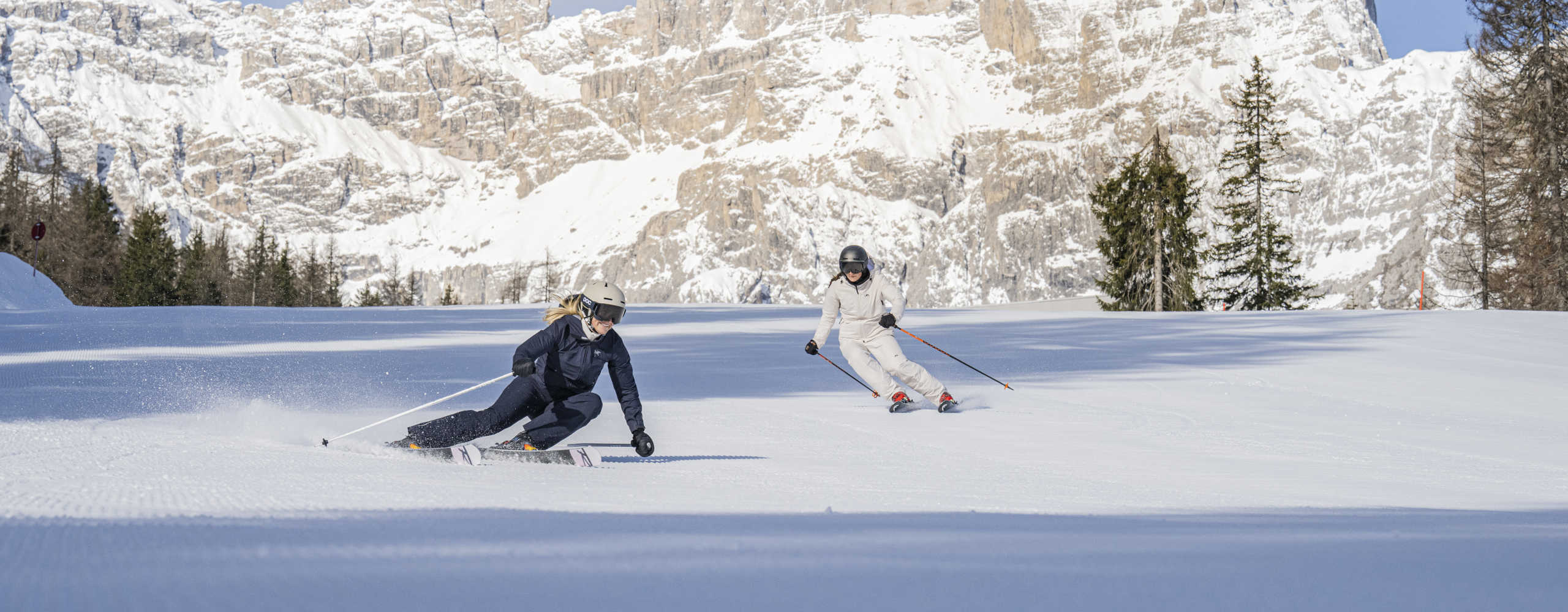 Skifahrer auf einer perfekt präparierten Piste in den 3 Zinnen Dolomiten vor beeindruckender verschneiter Bergkulisse.