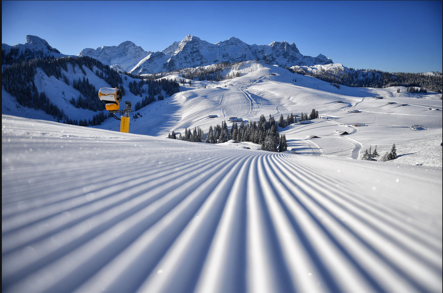 A freshly groomed ski slope in the Almenwelt Lofer, offering views of the snow-covered Loferer Steinberge and the expansive winter landscape of the Salzburg Alps.