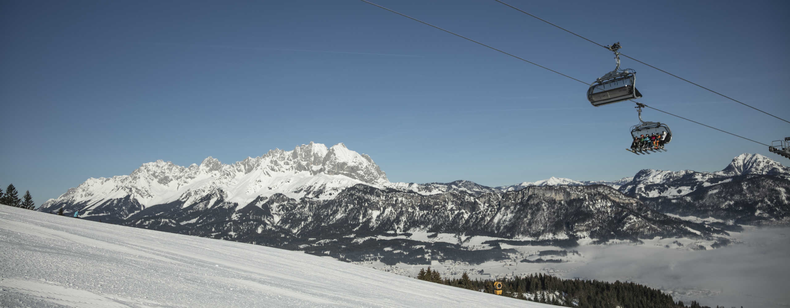 Skiing in St. Johann in Tirol with a chairlift and a view of the Wilder Kaiser in winter.