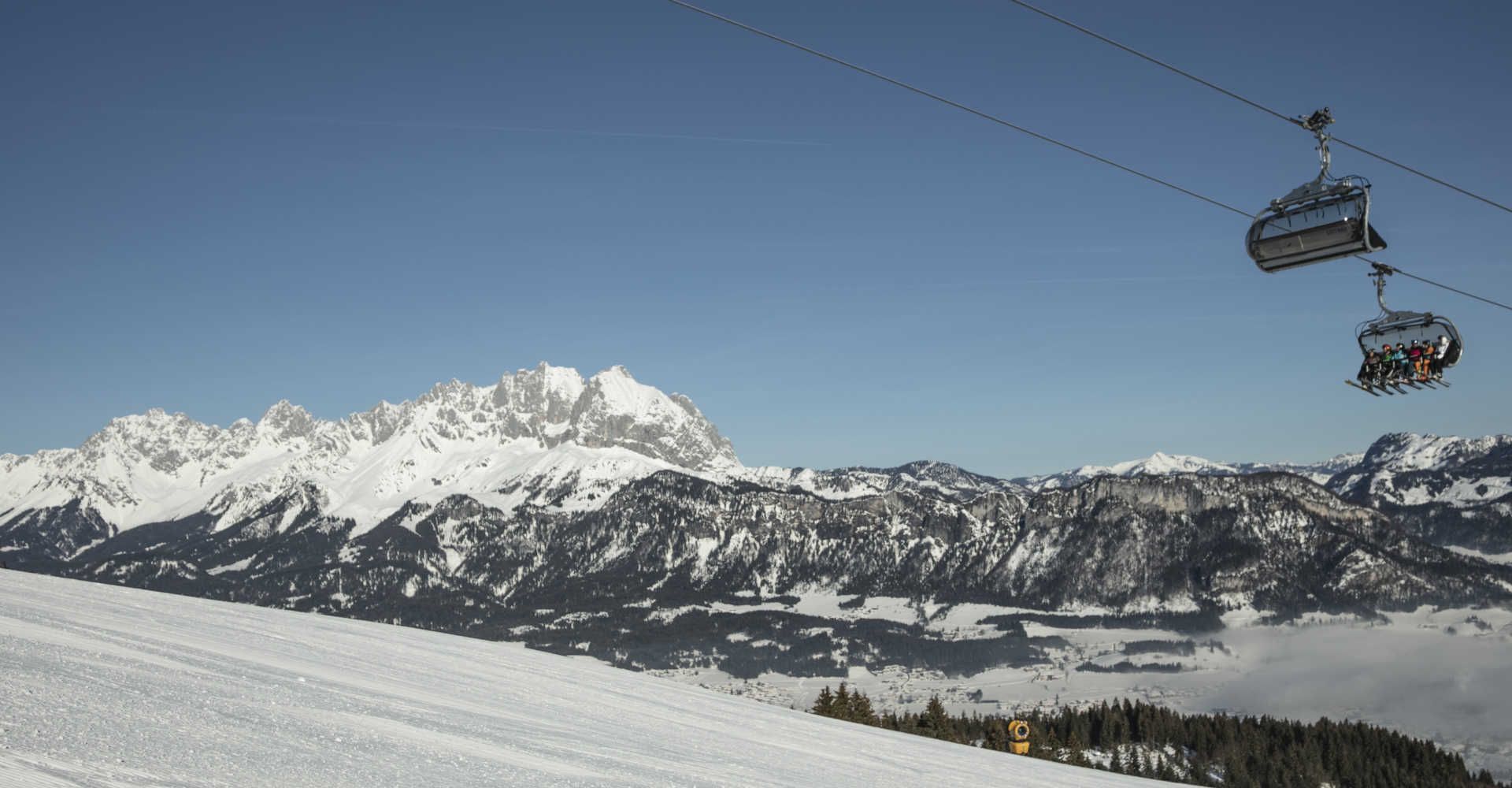 Skiing in St. Johann in Tirol with a chairlift and a view of the Wilder Kaiser in winter.
