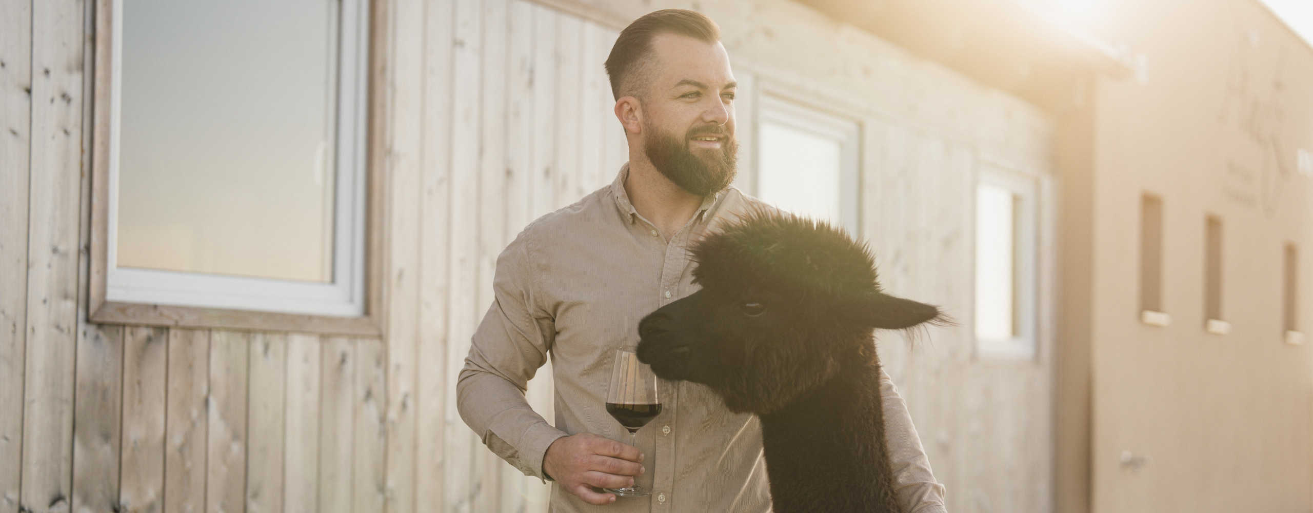 Person mit Rotwein in der Hand und einen schwarzen Alpaka