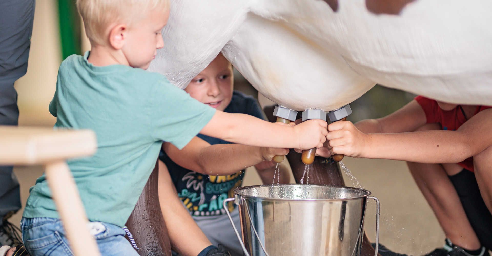 Kinder probieren im BIOS Nationalparkzentrum Mallnitz eine interaktive Melkstation aus und lernen spielerisch die Landwirtschaft kennen.