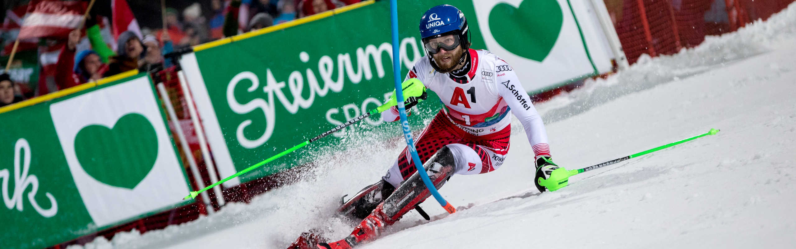 Skirennläufer beim Nightrace Schladming auf der Planai, umjubelt von tausenden Fans entlang der beleuchteten Rennstrecke.