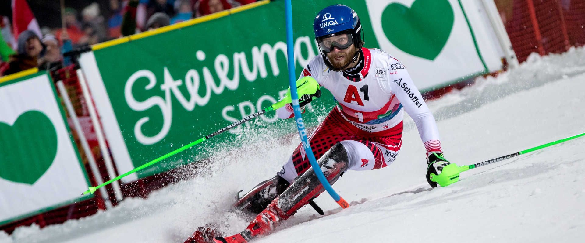 Skirennläufer beim Nightrace Schladming auf der Planai, umjubelt von tausenden Fans entlang der beleuchteten Rennstrecke.