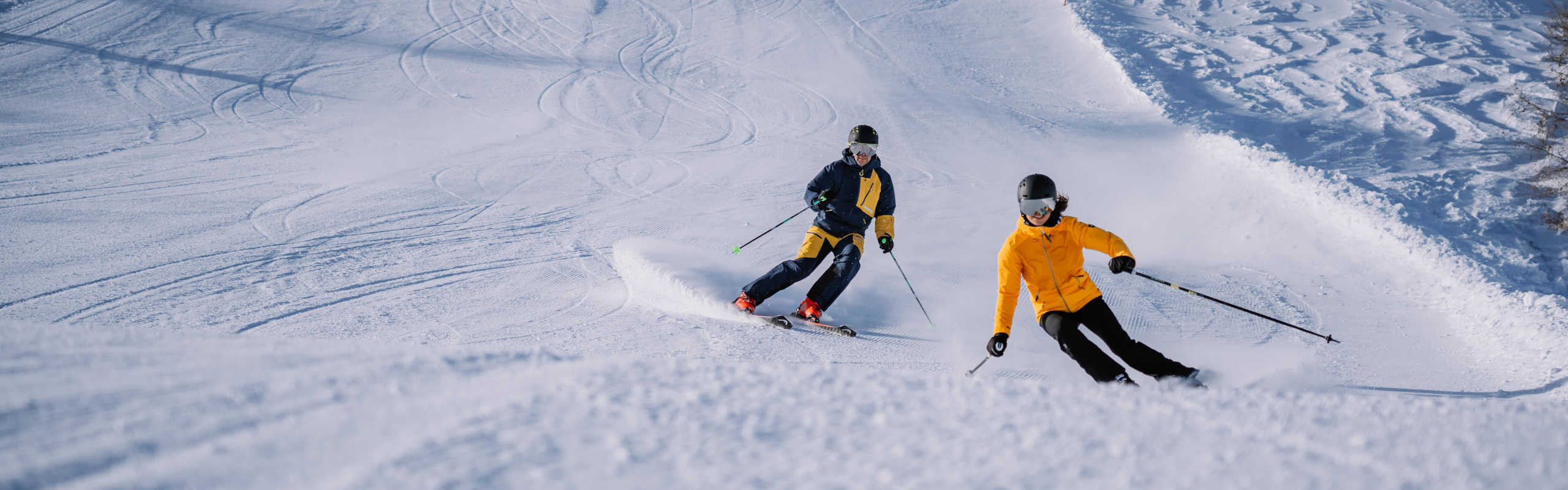 Zwei Skifahrer auf der Höss in Hinterstoder beim Carven auf einer perfekt präparierten Piste in der Region Pyhrn-Priel.