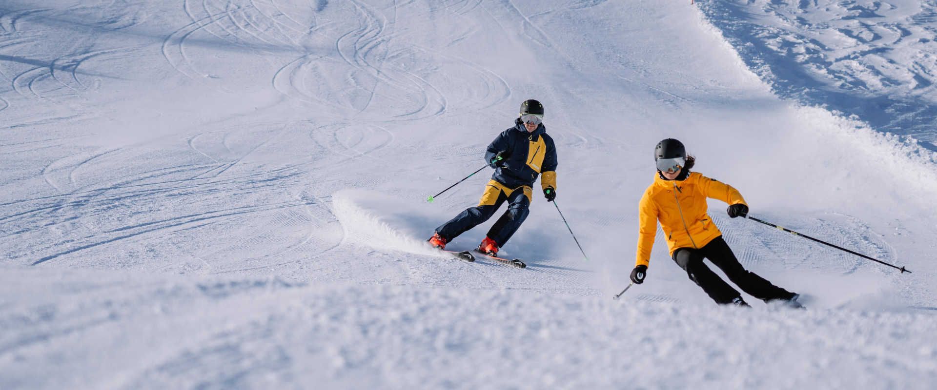 Zwei Skifahrer auf der Höss in Hinterstoder beim Carven auf einer perfekt präparierten Piste in der Region Pyhrn-Priel.