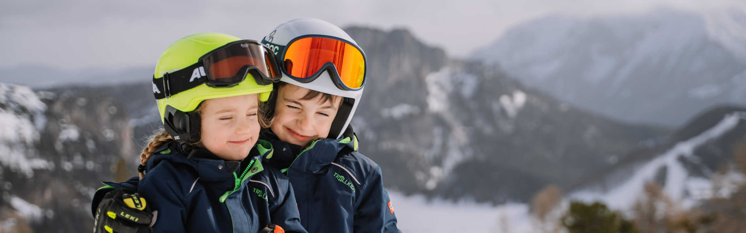 Children at the Wurzeralm in Pyhrn-Priel with their ski gear against a wintery Alpine backdrop.