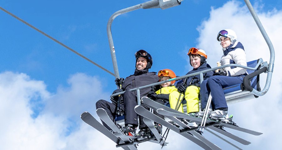 A family on a chairlift at Klippitztörl in Carinthia, on their way to the ski slopes in sunny winter weather.