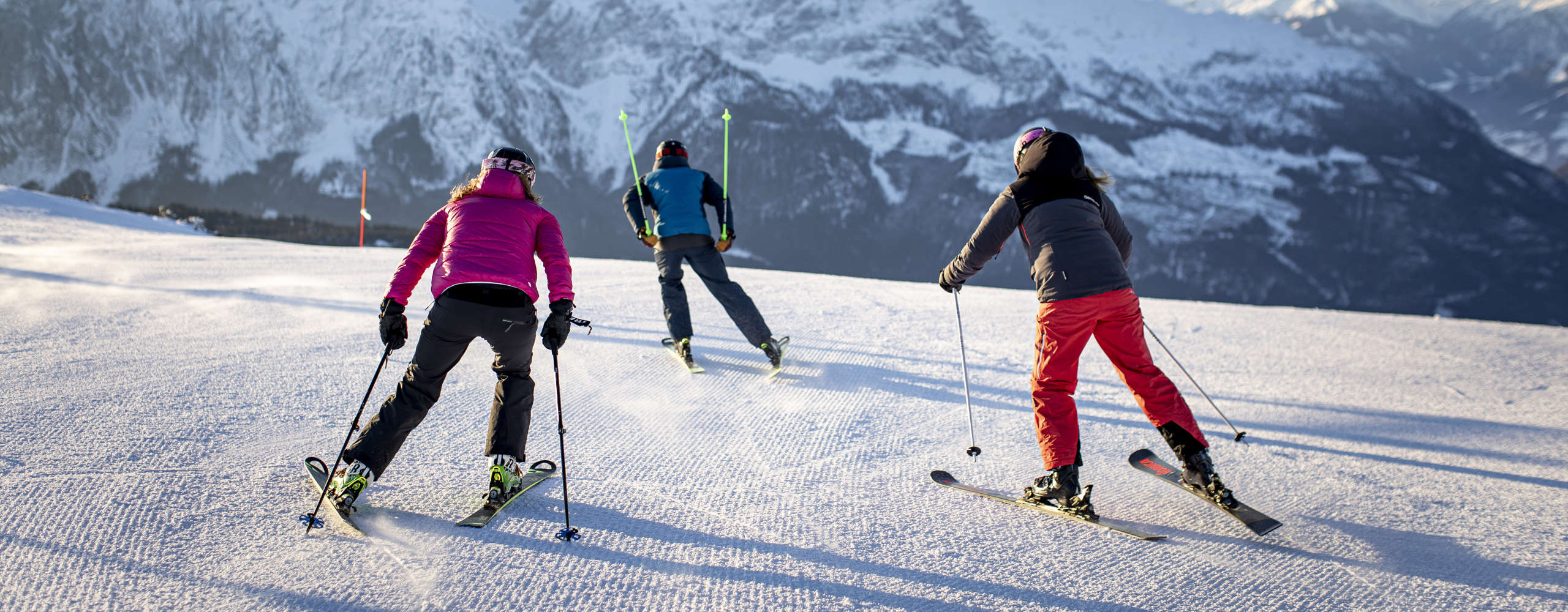 Skiers in Tauplitz enjoy a perfectly groomed slope against the backdrop of the impressive Alps.