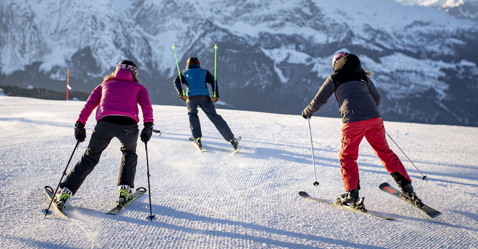 Skiers in Tauplitz enjoy a perfectly groomed slope against the backdrop of the impressive Alps.