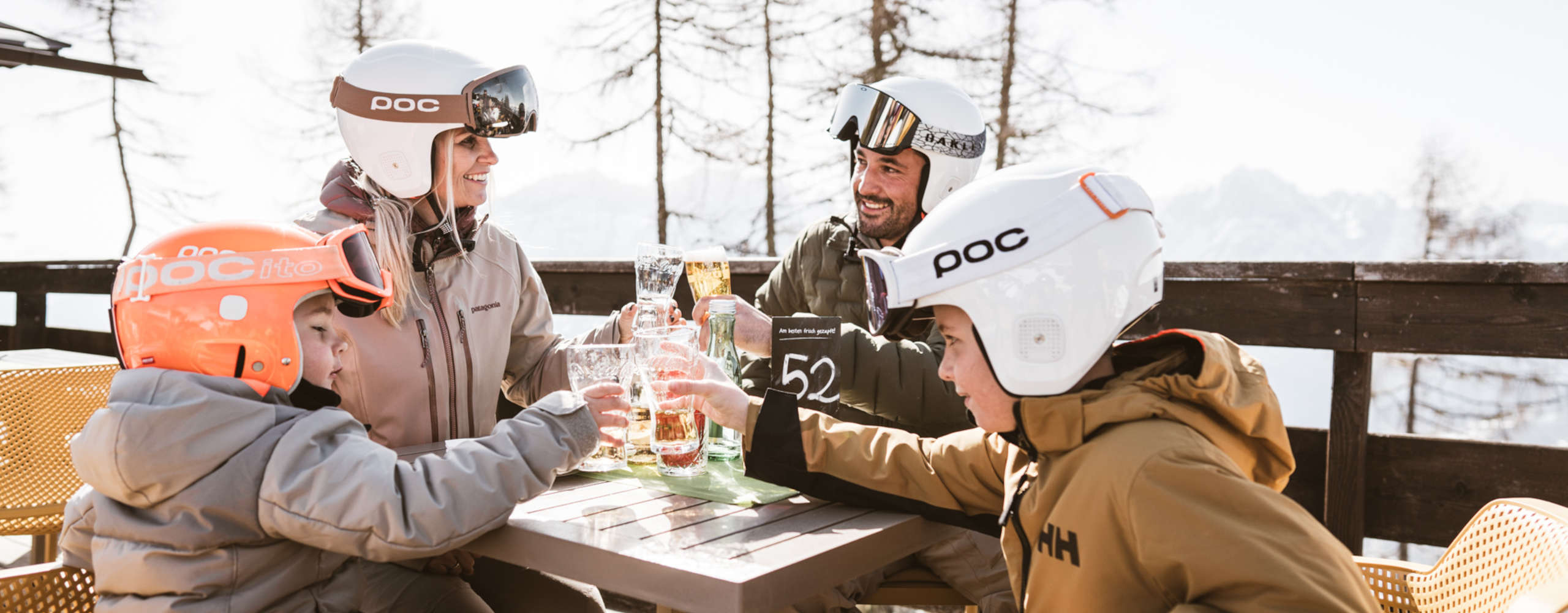 Familie bei der Einkehr auf einer Sonnenterrasse in Lienz in Osttirol nach einem Skitag.