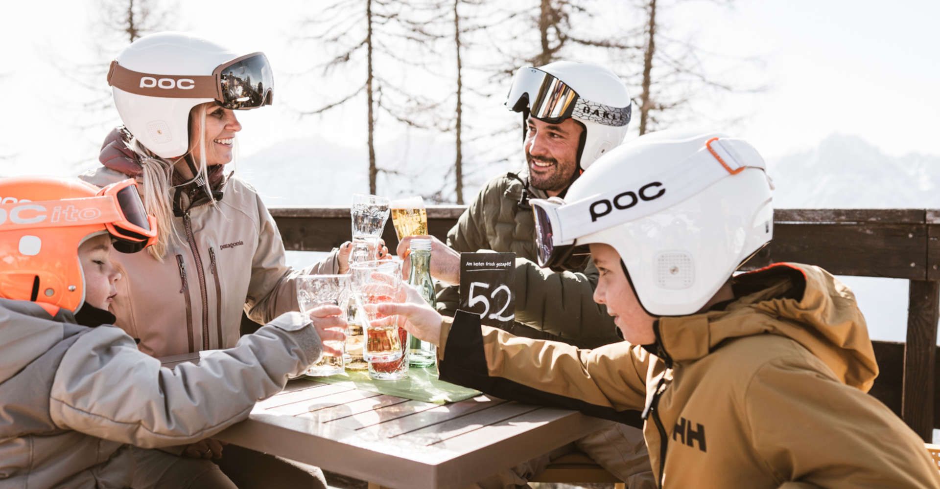 Familie bei der Einkehr auf einer Sonnenterrasse in Lienz in Osttirol nach einem Skitag.