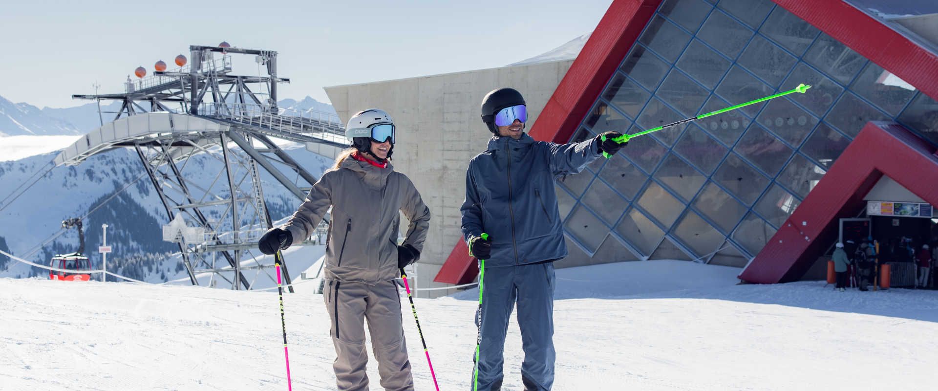 Skiers at the mountain station in Kitzbühel, featuring a modern cable car system and a panoramic view of the Alps.